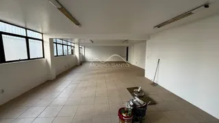 Corredor interno com piso de cerâmica e grandes janelas na parede esquerda.
