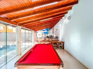 Sala de estar com mesa de bilhar e acesso a área externa com piscina.