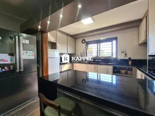 Foto de uma cozinha moderna com armários brancos e bancadas escuras em um imóvel em Lajeado.