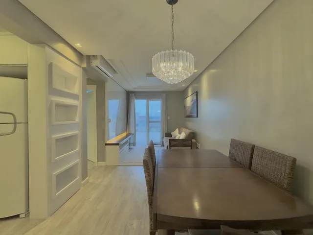 Foto de uma sala de jantar com mesa de madeira e iluminação clara.