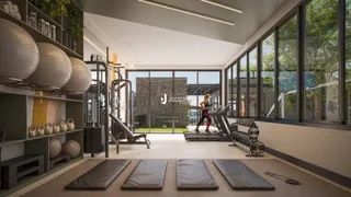 Imagem de uma área comum moderna com equipamentos de ginástica e grandes janelas.
