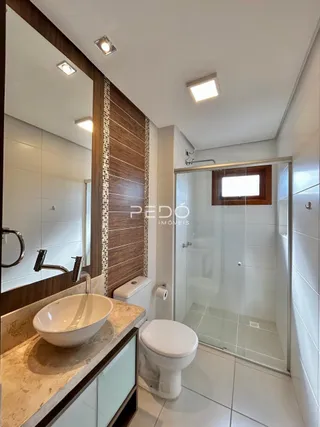 Banheiro moderno com box de vidro e piso cerâmico.