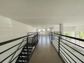 Corredor interno com escadas e paredes brancas.