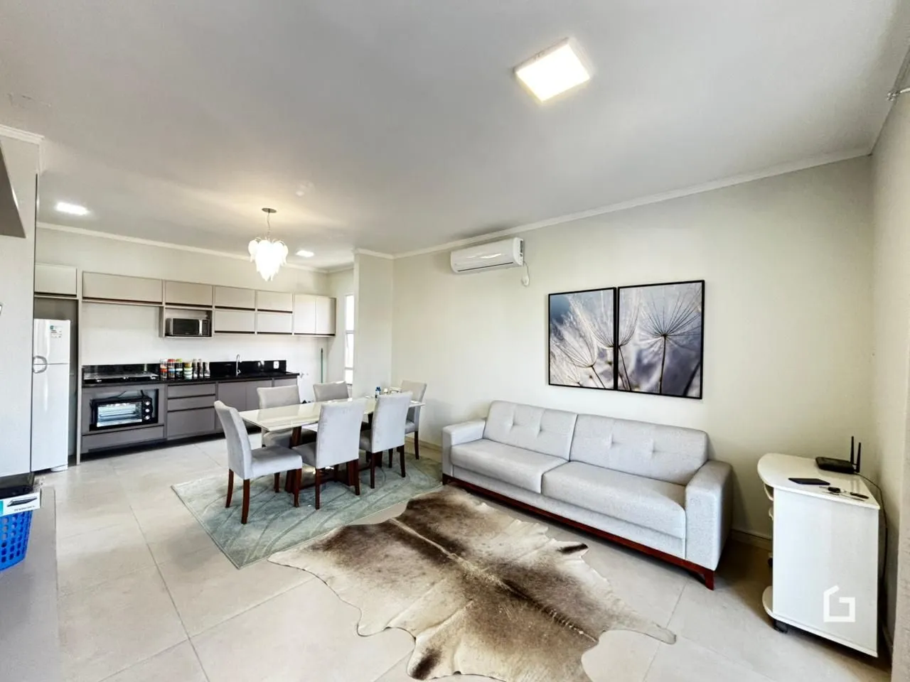 Sala de estar e cozinha com piso claro e sofá.