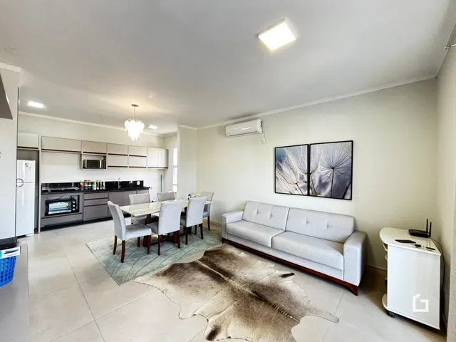 Sala de estar e cozinha com piso claro e sofá.