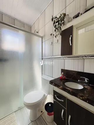 Banheiro com revestimento de azulejo e bancada escura.