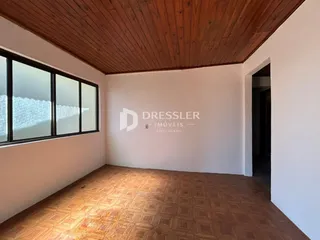 Ambiente interno com piso de ladrilhos e teto de madeira em uma residência.