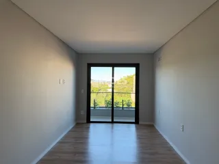 Interior de uma sala com piso de madeira e porta de vidro.