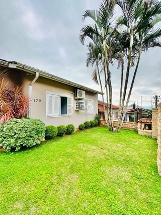 Fachada de uma casa em Lajeado, Brasil com jardim gramado e palmeiras.