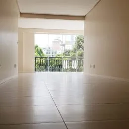 Vista de um ambiente interno com piso claro e grande abertura para o exterior.