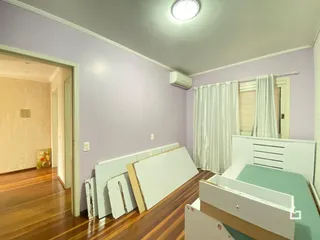 Quarto com piso de madeira e paredes roxas na residência.