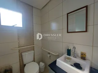 Foto de um banheiro interno com azulejos brancos e louças sanitárias.