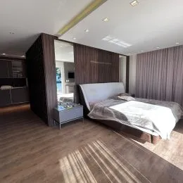 Quarto com cama e piso de madeira clara.
