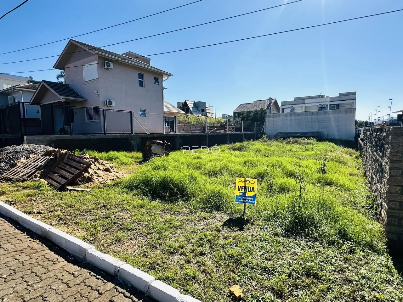 Vista da fachada de uma casa em Lajeado, Brasil, com terreno gramado e muro de contenção.