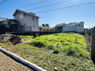 Vista da fachada de uma casa em Lajeado, Brasil, com terreno gramado e muro de contenção.