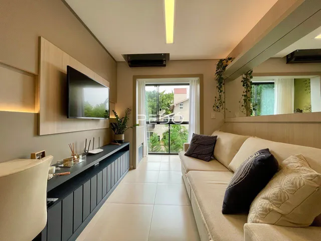 Sala de estar com sofá e televisão em um apartamento.