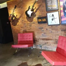 Sala de estar com parede de tijolos aparentes e banco vermelho.