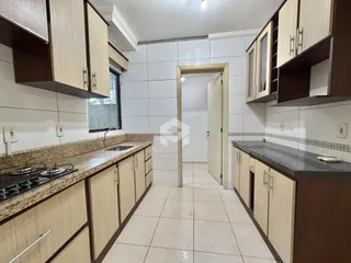Foto de uma cozinha com armários de madeira e revestimento branco.