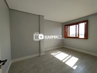 Uma sala de estar ampla com paredes cinzas e piso claro é visível na foto.
