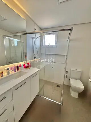 Foto de um banheiro moderno com box de vidro e bancada branca.