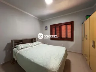Quarto com cama de casal e janela com persianas de madeira.