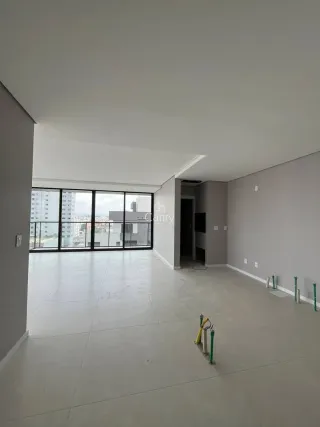 Ambiente interno amplo com piso claro e grandes janelas que oferecem vista urbana.