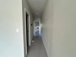 Corredor interno de uma residência com paredes brancas e piso claro.