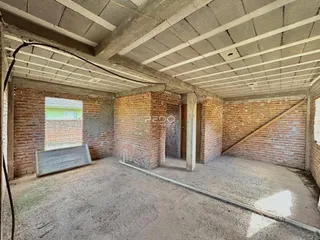 Interior de uma estrutura com paredes de tijolo aparente e teto de concreto.