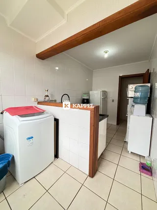 Cozinha com piso de cerâmica e máquina de lavar roupa visível.