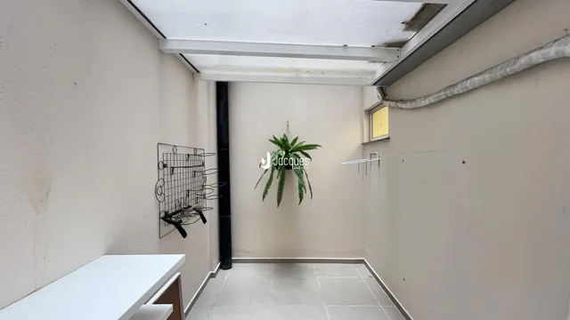 Corredor interno com paredes brancas e piso de cerâmica.