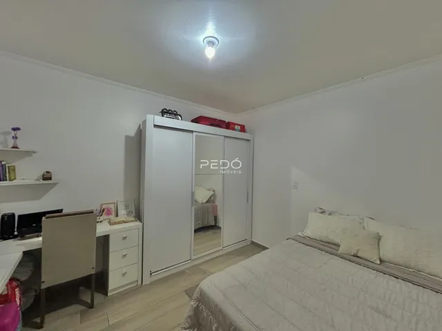 Quarto com guarda-roupa branco e piso de madeira clara.
