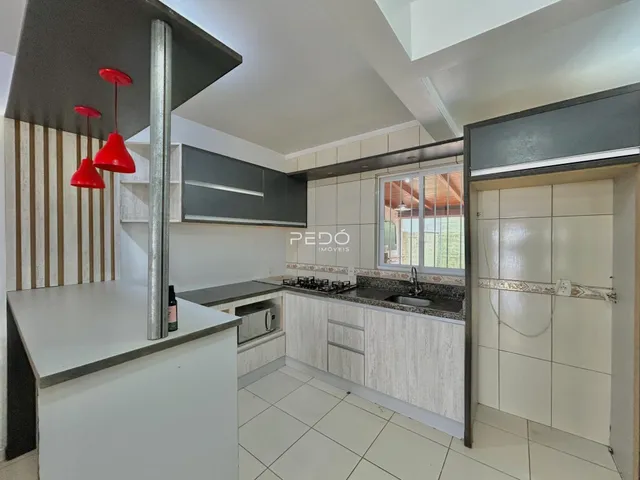 Foto de uma cozinha moderna com armários brancos e piso claro.