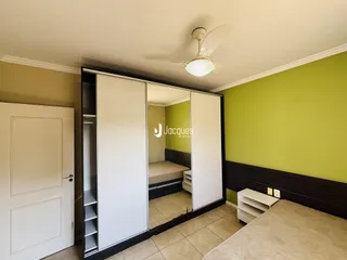 Quarto com parede verde e espelho refletindo o ambiente.