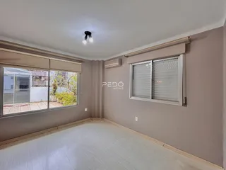 Sala de estar com piso claro e grandes janelas.