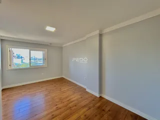 Sala de estar com piso de madeira e janela de vista para a cidade.