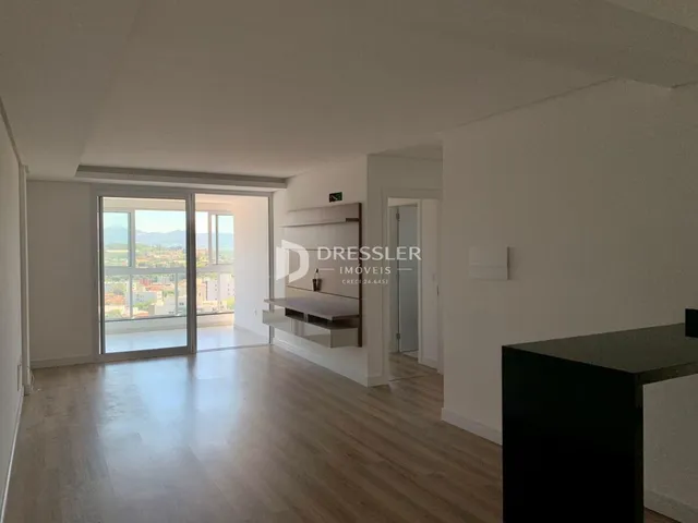 Sala de estar com piso de madeira e portas de vidro abrindo para a vista externa.