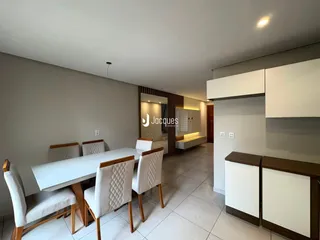 Uma sala de jantar moderna com mesa e cadeiras brancas em um apartamento.