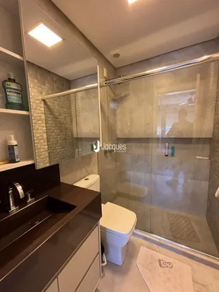 Foto de um banheiro com box de vidro e piso de porcelanato.