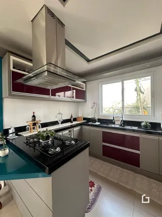 Vista da cozinha moderna com armários brancos e detalhes em vermelho.