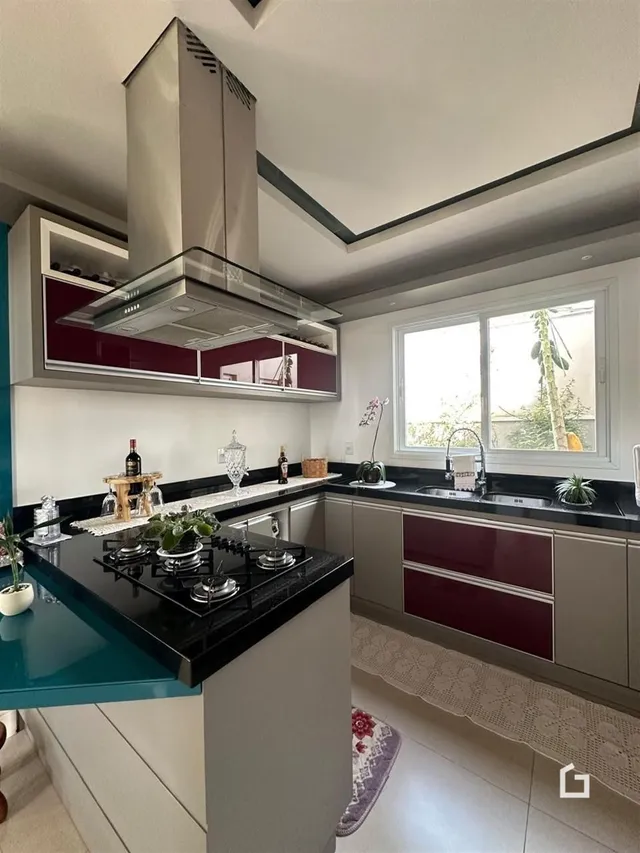 Vista da cozinha moderna com armários brancos e detalhes em vermelho.