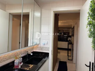 Vista de um banheiro com bancada escura e espelho grande.
