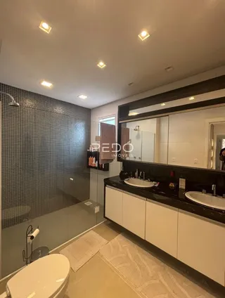 Vista interna de um banheiro com louças sanitárias e bancada escura.