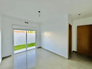 Ambiente interno de uma sala ampla com piso de cerâmica e porta de vidro.