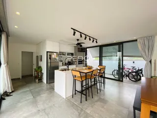 Sala de estar e cozinha moderna com portas de vidro que dão acesso a uma área externa.