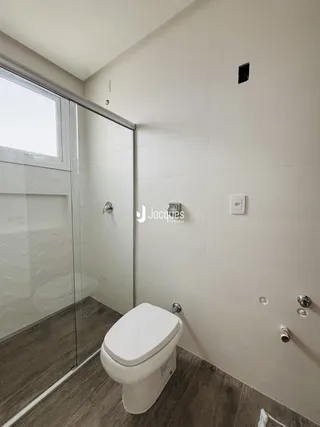 Foto interna de um banheiro com piso de cerâmica e box de vidro.