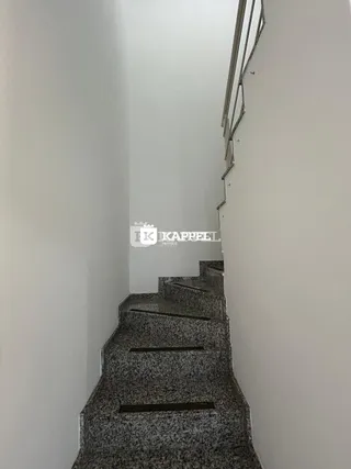 Uma foto mostra um corredor com escadas em uma residência.