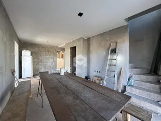 Interior de uma sala em construção com paredes de concreto aparente.