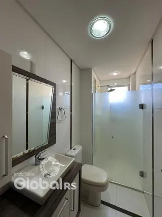 Foto de um banheiro interno com box de vidro e louças sanitárias.