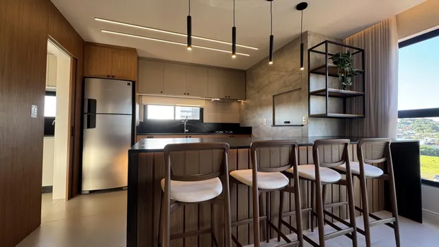 Foto de uma cozinha moderna com bancadas escuras e balcão com banquetas de madeira.