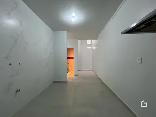Corredor interno de uma residência com paredes brancas e piso claro.